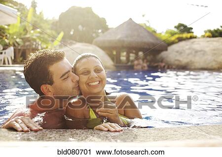 Stock Image - Couple hugging in swimming pool. Fotosearch