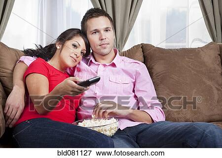 Couple sitting on sofa and watching television View Large Photo Image Stock Photo - Couple sitting on sofa and watching television. Fotosearch