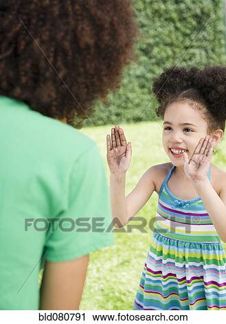 Stock Image - Daughter showing dirty hands to mother. Fotosearch