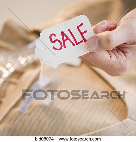 Stock Image - Hand holding clothing sale tag. Fotosearch