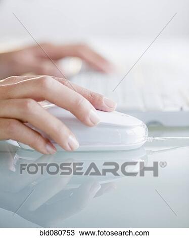 Stock Image - Hands operating computer mouse and keyboard. Fotosearch