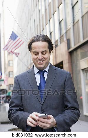 Hispanic businessman text messaging in city View Large Photo Image Stock Image - Hispanic businessman text messaging in city. Fotosearch