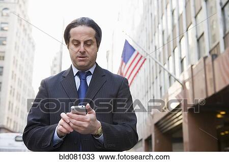Hispanic businessman text messaging in city View Large Photo Image Stock Image - Hispanic businessman text messaging in city. Fotosearch