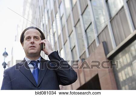 Hispanic businessman using cell phone in city View Large Photo Image Picture - Hispanic businessman using cell phone in city. Fotosearch
