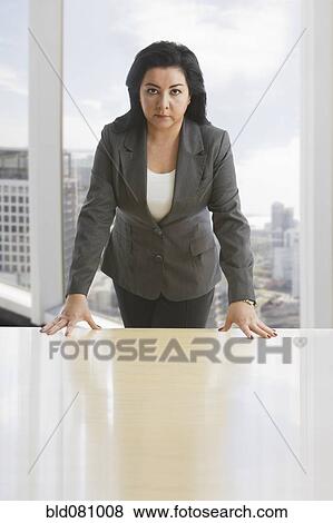 Stock Photo - Hispanic businesswoman leaning on desk. Fotosearch