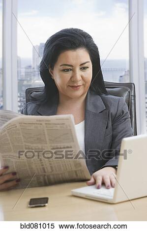 Hispanic businesswoman reading newspaper and using laptop View Large Photo Image Stock Photography - Hispanic businesswoman reading newspaper and using laptop. Fotosearch