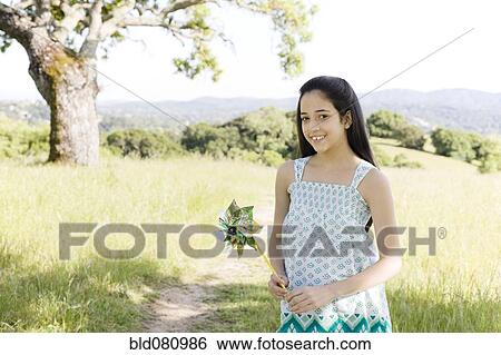 Stock Photograph - Hispanic girl holding pinwheel in field. Fotosearch