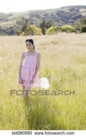Stock Image - Hispanic girl in field holding net. Fotosearch