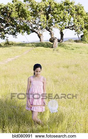 Stock Image - Hispanic girl in field holding net. Fotosearch