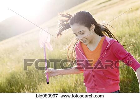 Stock Photo - Hispanic girl running in field with net. Fotosearch