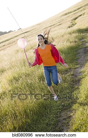 Stock Photograph - Hispanic girl running in field with net. Fotosearch