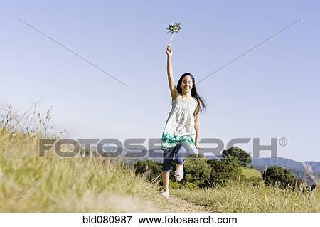 Stock Photo - Hispanic girl running with pinwheel. Fotosearch