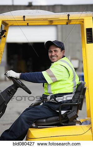 Stock Photo - Hispanic man driving forklift. Fotosearch