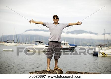 Hispanic man standing at waterfront View Large Photo Image Stock Photo - Hispanic man standing at waterfront. Fotosearch