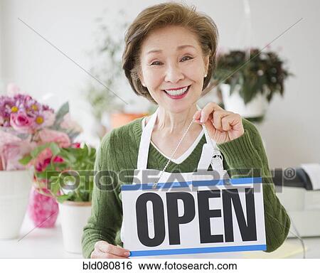 Stock Photograph - Japanese florist holding open sign. Fotosearch