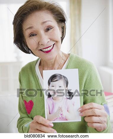 Japanese woman holding photograph of girl View Large Photo Image Picture - Japanese woman holding photograph of girl. Fotosearch
