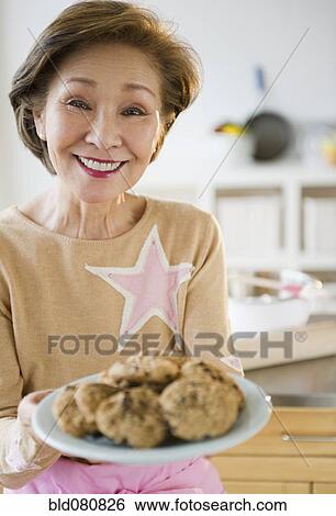 Stock Photograph - Japanese woman holding plate of cookies. Fotosearch
