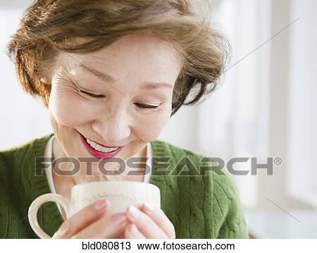 Stock Image - Japanese woman looking into cup. Fotosearch