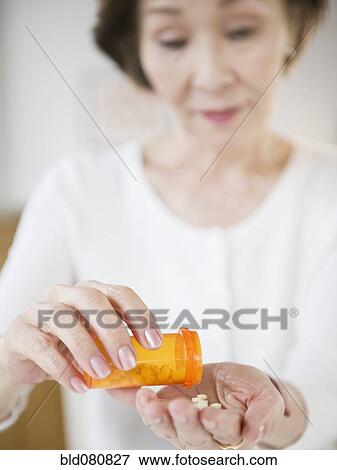 Japanese woman pouring medicine into hand View Large Photo Image Stock Photo - Japanese woman pouring medicine into hand. Fotosearch