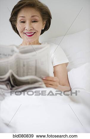 Japanese woman reading newspaper in bed View Large Photo Image Stock Photo - Japanese woman reading newspaper in bed. Fotosearch