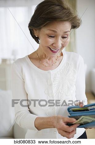 Stock Image - Japanese woman removing money from wallet. Fotosearch