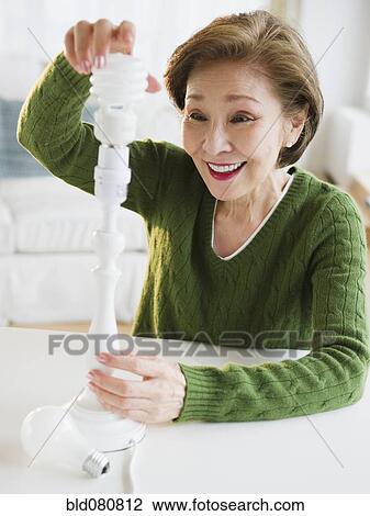 Japanese woman replacing energy efficient light bulb View Large Photo Image Stock Image - Japanese woman replacing energy efficient light bulb. Fotosearch