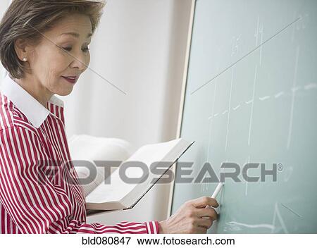 Stock Photo - Japanese woman writing on chalk board. Fotosearch