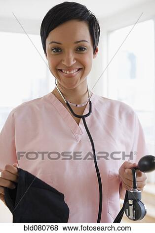 Stock Photo - Mixed race doctor holding blood pressure gauge. Fotosearch