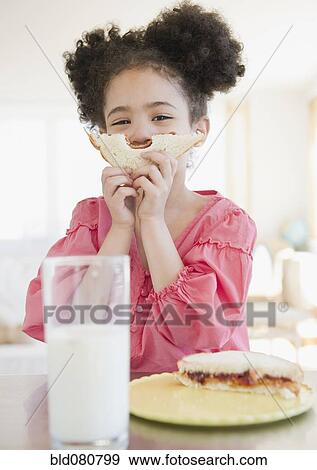 Stock Photo - Mixed race girl holding sandwich in front of face. Fotosearch