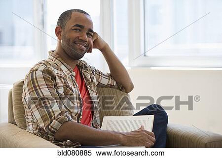 Mixed race man sitting in armchair reading book View Large Photo Image Stock Photography - Mixed race man sitting in armchair reading book. Fotosearch