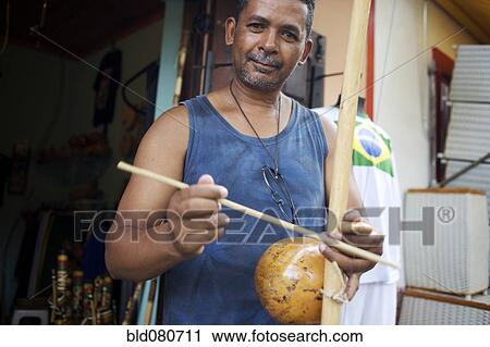 Mixed race man standing with musical instrument View Large Photo Image Stock Image - Mixed race man standing with musical instrument. Fotosearch