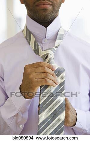 Picture - Mixed race man tying tie. Fotosearch