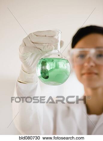 Stock Image - Mixed race researcher holding eco-friendly beaker. Fotosearch