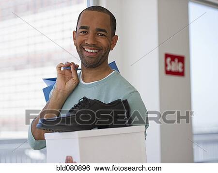Stock Photograph - Mixed race shopper holding shoe and box. Fotosearch
