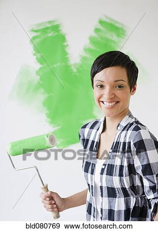 Mixed race woman holding paint roller with green paint View Large Photo Image Stock Photo - Mixed race woman holding paint roller with green paint. Fotosearch
