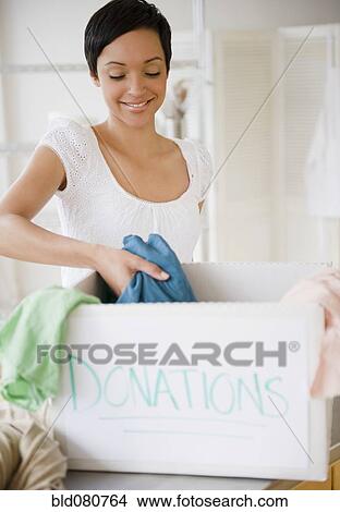 Mixed race woman putting clothing in donation box View Large Photo Image Picture - Mixed race woman putting clothing in donation box. Fotosearch