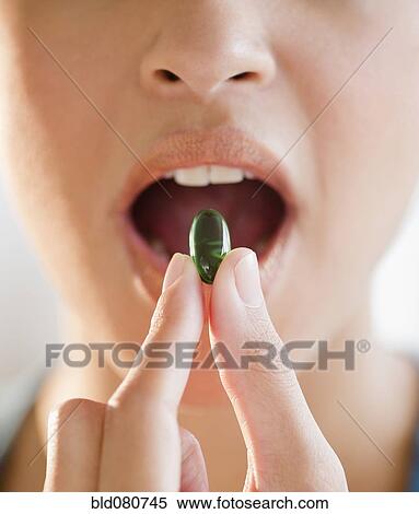 Mixed race woman putting green capsule into mouth View Large Photo Image Stock Photography - Mixed race woman putting green capsule into mouth. Fotosearch