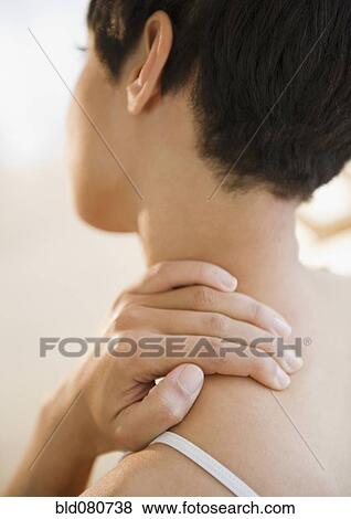 Stock Photo - Mixed race woman rubbing neck and shoulder. Fotosearch