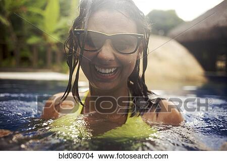 Mixed race woman wearing sunglasses in swimming pool View Large Photo Image Picture - Mixed race woman wearing sunglasses in swimming pool. Fotosearch