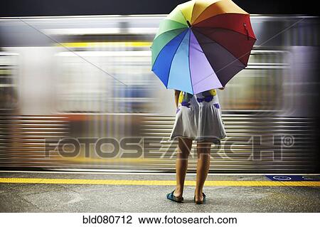 Mixed race woman with umbrella on train platform View Large Photo Image Stock Image - Mixed race woman with umbrella on train platform. Fotosearch