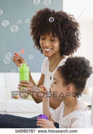 Stock Photo - Mother and daughter blowing bubbles. Fotosearch