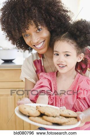 Stock Photograph - Mother and daughter holding plate of cookies. Fotosearch