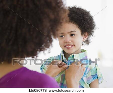 Mother buttoning shirt of daughter View Large Photo Image Stock Photo - Mother buttoning shirt of daughter. Fotosearch