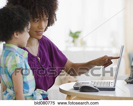 Stock Photography - Mother pointing to laptop with daughter. Fotosearch