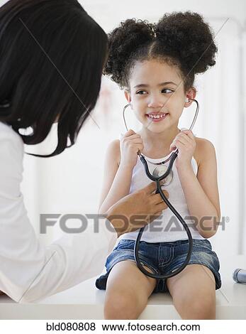 Pediatrician helping patient listen to heartbeat View Large Photo Image Stock Photo - Pediatrician helping patient listen to heartbeat. Fotosearch
