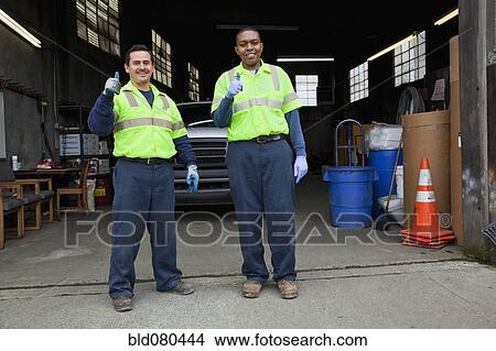Picture - Sanitation workers giving thumbs up in garage. Fotosearch