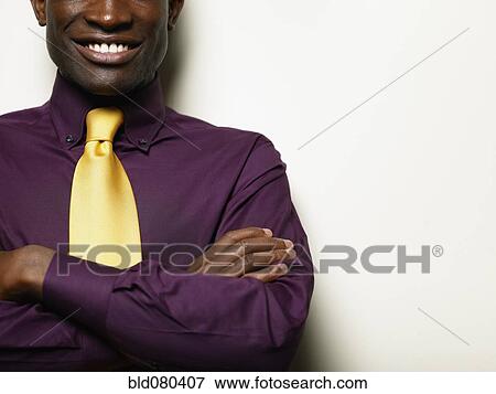 Stock Photo - Smiling Black businessman with arms crossed. Fotosearch