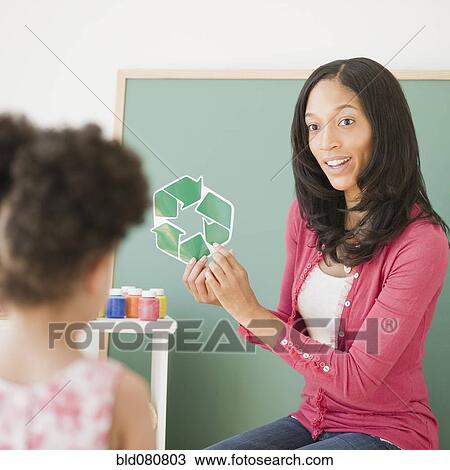 Stock Image - Teacher showing recycling symbol to student. Fotosearch