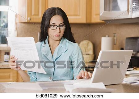 Stock Photo - Turkish woman paying bills using laptop. Fotosearch