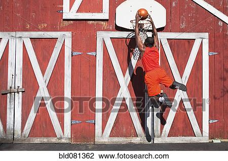 Black man dunking basketball outside barn View Large Photo Image Stock Image - Black man dunking basketball outside barn. Fotosearch